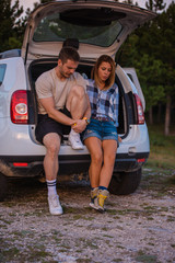 Young couple sitting on the back of a off road vehicle and enjoying the view from inside the all terrain vehicle at sunset.