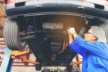 Close-up of car mechanic working under car in auto repair service.