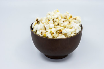 Popcorn in wooden bowl isolated on white background. Selective focus.