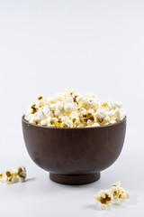 Popcorn in wooden bowl isolated on white background. Selective focus.