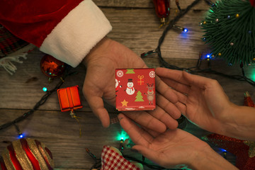 Santa Claus offering a small gift box to a happy woman on a festive Christmas decor