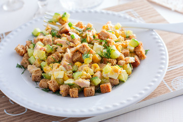 salad with smoked ham, corn, crackers on a white plate, horizontal