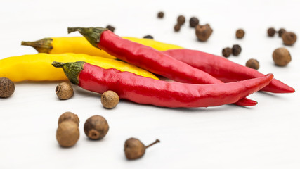Small chilli peppers and pepper peas on white wooden table.