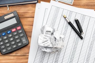 Crumpled tax form with financial documents, calculator and notepad on the table. Top view. Business...