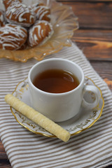 A Cup of fragrant tea and delicious sweet cookies on a wooden background.
