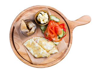 Omelette with vegetables and bread on wooden cutting board on white background. Isolated on white