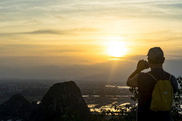 Tourist staying on the top of mountain and taking a photos of Marble mountains and beautiful Da Nang city view with jungle and sea in sunset,travelling concept