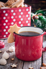 Red tea mug with cookies in Christmas decorations on a wooden table, selective focus