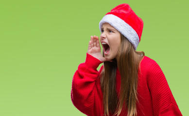 Young beautiful girl wearing christmas hat over isolated background shouting and screaming loud to side with hand on mouth. Communication concept.