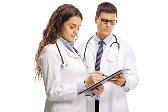 Two young doctors looking at a paper on a clipboard
