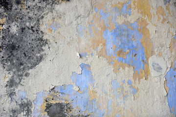 Beautiful colors layers of an outdoor plaster wall showing several times of wall repairing. Each color showing a new layer had been added to hide the old one below from time to time. 