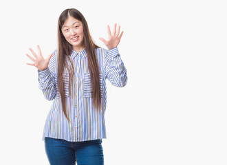 Young Chinese woman over isolated background showing and pointing up with fingers number ten while smiling confident and happy.