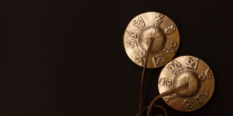 Tibetan karatal meditation lies on the black floor. Minimalistic concept of relaxation, tranquility and concentration. Tibetan ringing plates Tingsha for relaxation and recovery during meditation.