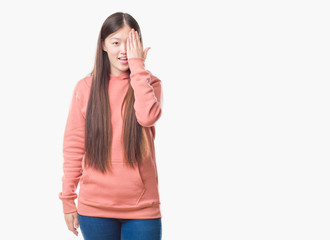 Young Chinese woman over isolated background wearing sport sweathshirt covering one eye with hand with confident smile on face and surprise emotion.