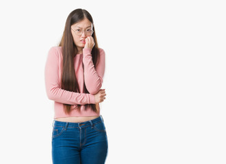 Young Chinese woman over isolated background wearing glasses looking stressed and nervous with hands on mouth biting nails. Anxiety problem.