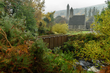 A wooden bridge, medieval church and round tower during autumn