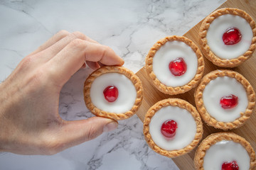 Delicious baked tarts cakes top down flat lay shot mans hand takes cake marble background