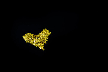 Golden stars confetti on dark black background. Holiday concept. Many objects, horizontal view, top view