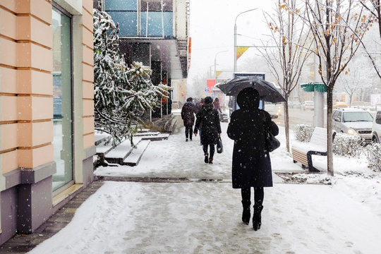 Winter, The City, A Woman In A Black Coat Goes Under A Black Umbrella On The Sidewalk, It Is Sleet