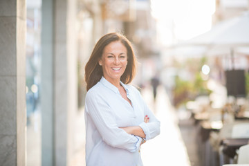 Beautiful middle age hispanic woman standing with smile on face at the street. Walking through the...