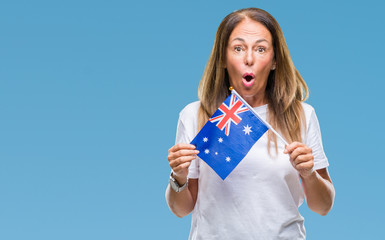 Middle age hispanic woman holding flag of Australia over isolated background scared in shock with a surprise face, afraid and excited with fear expression