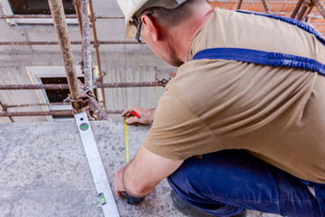 Civil engineer is marking point with pencil on concrete at building site