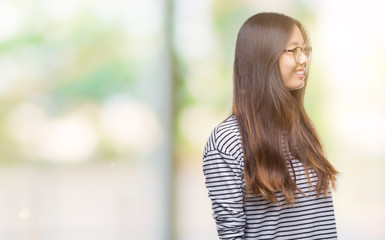 Young asian woman wearing glasses over isolated background looking away to side with smile on face, natural expression. Laughing confident.