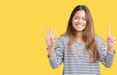 Young beautiful brunette woman wearing stripes sweater over isolated background showing and pointing up with fingers number six while smiling confident and happy.