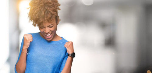 Beautiful young african american woman over isolated background very happy and excited doing winner...