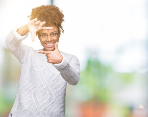 Beautiful young african american woman wearing winter sweater over isolated background smiling making frame with hands and fingers with happy face. Creativity and photography concept.