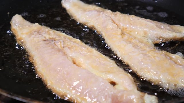 Battered gurnard fish fillets, frying in a pan of hot oil