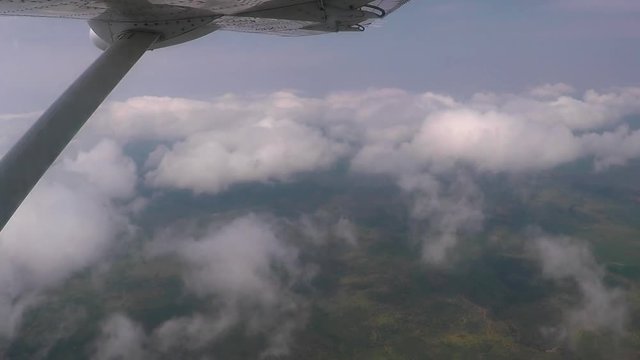 Aerial view flying across Kenya seeing glimpses of land below and then flying into a big cloud