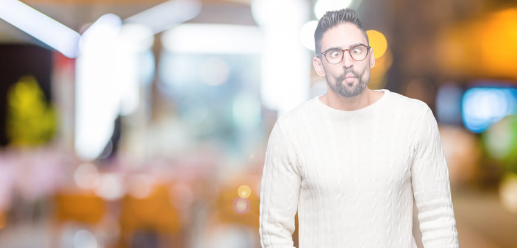Young handsome man wearing glasses over isolated background making fish face with lips, crazy and comical gesture. Funny expression.