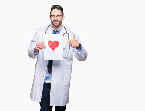 Handsome young doctor man holding paper with red heart over isolated background happy with big smile doing ok sign, thumb up with fingers, excellent sign