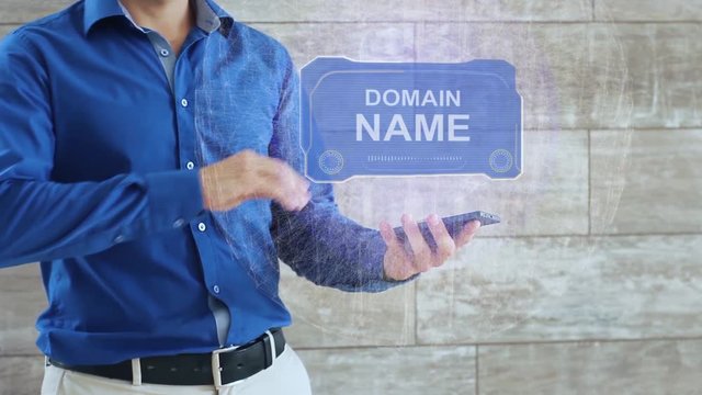Man activates a conceptual HUD hologram with text Domain name. The guy in the blue shirt and light trousers with a holographic screen on the background of the wall