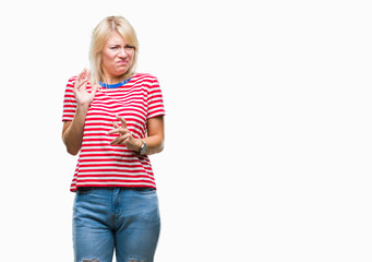 Young beautiful blonde woman over isolated background disgusted expression, displeased and fearful doing disgust face because aversion reaction. With hands raised. Annoying concept.