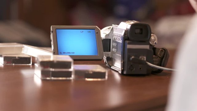 Man rewinds mini DV cassette tape in miniDV video camera camcorder