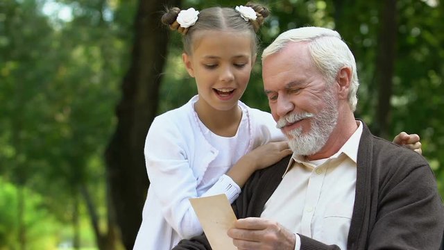 Grandfather showing picture to granddaughter and telling interesting story