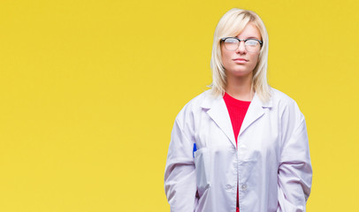 Young beautiful blonde professional woman wearing white coat over isolated background with serious expression on face. Simple and natural looking at the camera.