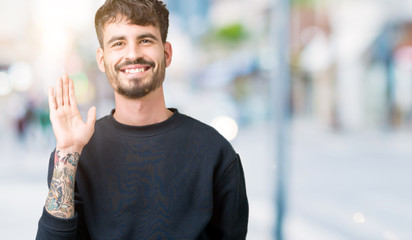 Young handsome man over isolated background Waiving saying hello happy and smiling, friendly welcome gesture
