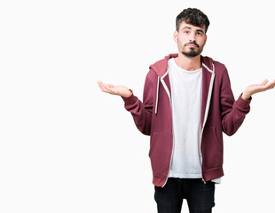 Young handsome man over isolated background clueless and confused expression with arms and hands...