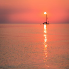 Sun resting on a sailing boat mast in living coral color sunrise, color of the year 2019. Travel...