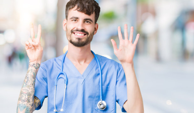 Young handsome nurse man wearing surgeon uniform over isolated background showing and pointing up with fingers number seven while smiling confident and happy.