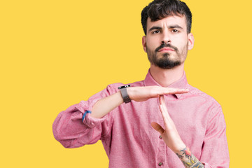 Young handsome man wearing pink shirt over isolated background Doing time out gesture with hands,...