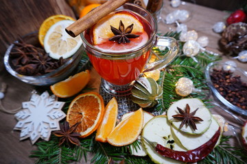 Wine mulled with spices and dried citruses on a table on the background of lights. Christmas mulled...