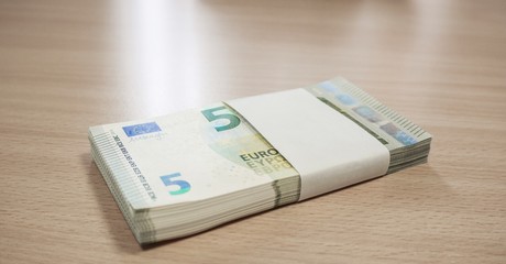 Stack of 5 Euro notes on a pine desk