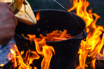Tourist bowler with food on bonfire, cooking in the hike, outdoor activities. Preparation of pilaf.