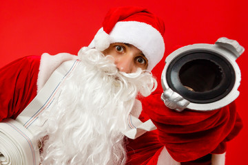 Christmas man in santa clothes with fire Hose standing against isolated red background
