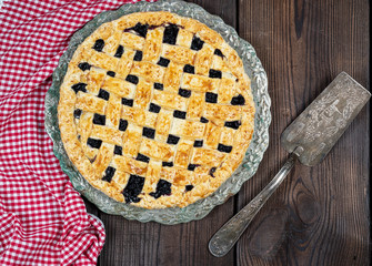 baked round black currant cake on an iron plate