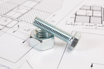 Technical drawings of bolt and nut. Engineering, technology and metalworking. Metal bolt and nut on printed drawings background.